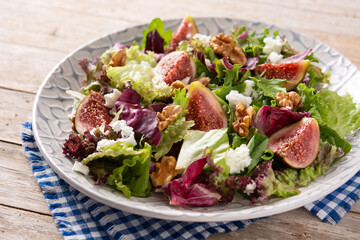 Figs salad with cheese and walnuts on wooden table.