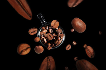  coffee beans fly into a mug with coffee isolated on black background top view