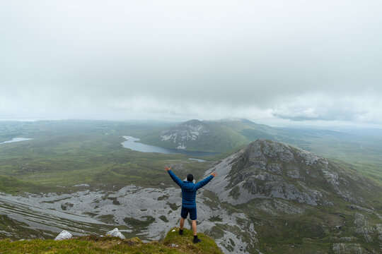 Man standing on top of mountain raising his arms in Errigal mountain Co. Donegal Ireland