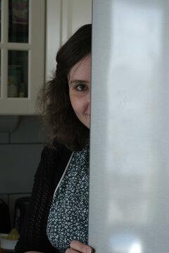 Portrait Of A Smiling Woman Hiding Behind A Door In A Kitchen