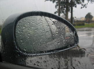 Rétroviseur de voiture sous un ciel pluvieux avec les gouttes de pluie