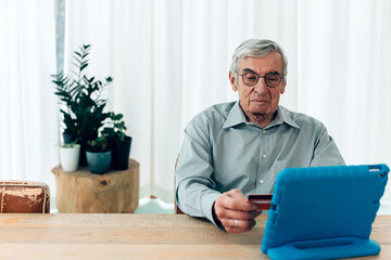 elderly man makes online digital payment using credit card and tablet