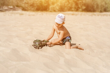 Little boy playing with a toy car on the sand