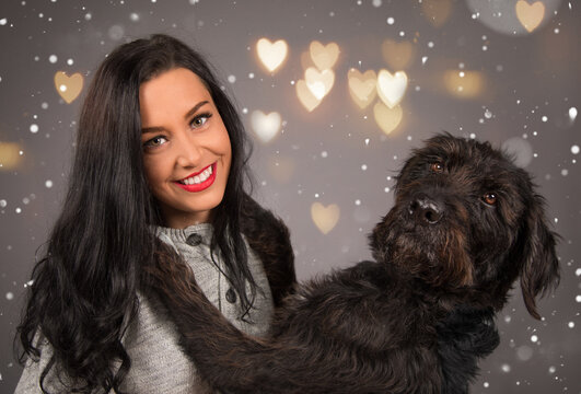 Happy brunette girl with her dog, grey background.