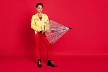Photo of adorable shiny young woman dressed leather jacket closing parasol empty space smiling isolated red color background