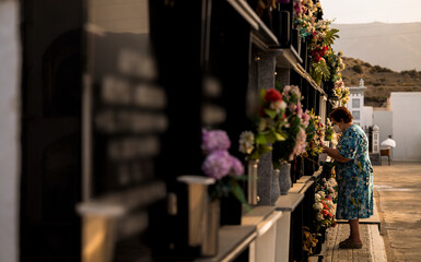 Naklejka na ściany i meble Old lady mourning her family in cemetery