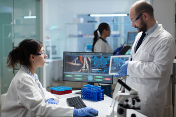 Medical team of biologist researcher working at coronavirus treatment during pharmacology examination in biomedical hospital laboratory. Biologist man holding tablet analyzing virus expertise