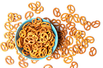 Salted pretzels are in a blue cup. They are also scattered around the cup. Isolated on white background. Top view.