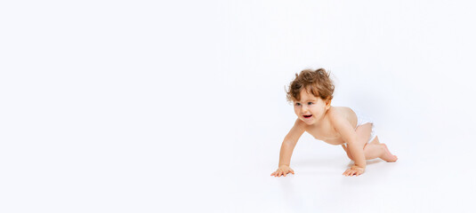 Portrait of little cute toddler boy, baby in diaper crawling isolated over white studio background....