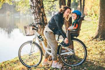 Naklejka na ściany i meble Happy family. mother and son riding a bicycle together outdoors in a city park.