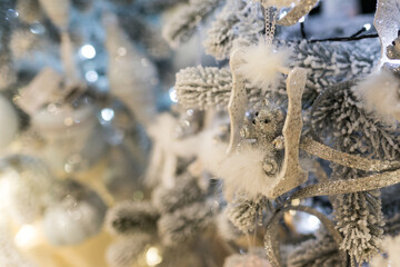 Close up of holidays location with soft toy and garlands on blue white Christmas tree