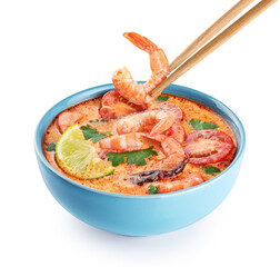 Tom yum noodle soup with spices and shrimp isolated on white background. Chopsticks hold shrimp. With clipping path.