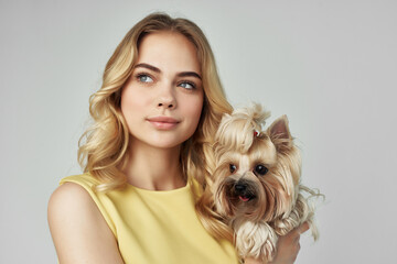 beautiful woman in a yellow dress fun a small dog isolated background