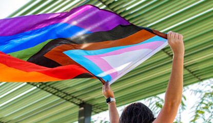 Female is holding the gay rainbow flag. Progress pride flag.