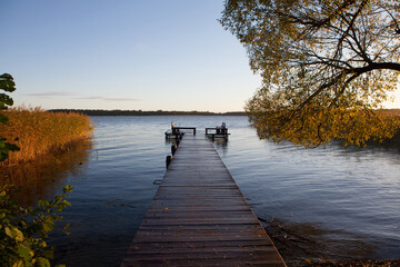 Fototapeta na wymiar Dawn on the shore of an autumn lake with a wooden pier.