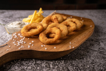 selective focus. fried onion rings in breadcrumbs fried in oil. with natural sauce. restaurant serving. on a dark background. for menus and ads