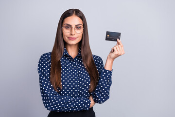 Fototapeta premium Portrait of attractive cheery smart clever businesswoman holding in hand bank card freelance isolated over grey color background