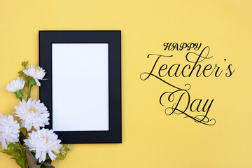 Teacher's day text and a blank photo frame decorated with white flowers on yellow background....