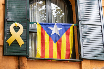 Catalan independence flag and yellow ribbon hanging from a window demanding the independence of Catalonia and the freedom of the imprisoned politicians
