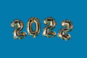 gold inflatable balloons shape numbers 2022 on a blue background, minimalism new year concept