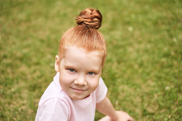 Little girl outdoor portrait. Red hair. Happy baby face. Female person at backyard. American smart schoolgirl. Positive child expression. Smile kid face. Summer time