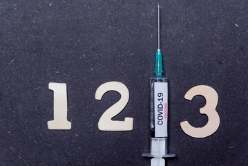 Third covid vaccine dose and jab concept with numbers. Syringe is seen on table as a concept for the 3rd covid-19 vaccine dose, also called booster shot - obrazy, fototapety, plakaty