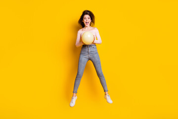 Fototapeta na wymiar Full size photo of young happy excited crazy cheerful woman jumping with balloon in hands isolated on yellow color background