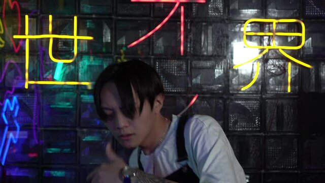 Young Asian man dancing hip hop indoors. Asian contemporary dancer. The inscription on the background in Japanese - Let from darkness to light.