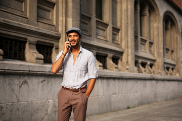 Young stylish man talking to the phone outdoors. Fashion happy man  enjoy outdoors