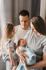 Portrait of loving family with newborn son and infant daughter. Happy caucasian family of four people. Sister meets her newborn brother. Selective focus