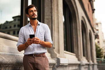 Young stylish man using the phone outdoors. Fashion happy man  enjoy outdoors