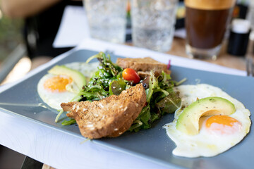 Tasty healthy breakfast with salad, tomato, avocado, fried eggs and bread, concept of vegetarianism
