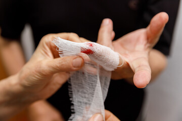 Applying a bandage to the wound of a man's finger. The man neglected precautions and cut his hand....