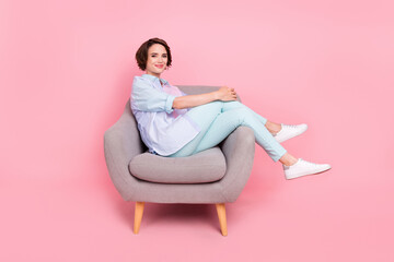 Full length body size photo young woman sitting in armchair wearing casual outfit isolated pastel pink color background