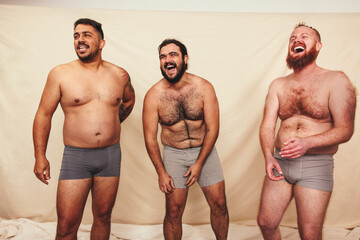 Three shirtless men laughing in a studio - Powered by Adobe