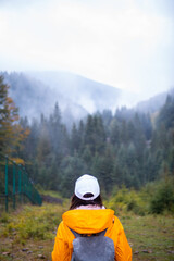 Fototapeta na wymiar woman in yellow raincoat hiker in autumn mountains