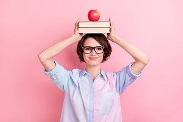 Photo of young woman happy positive smile hold books apple on head balance isolated over pastel...