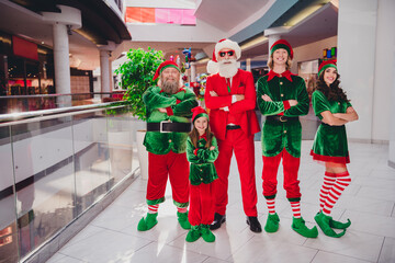 Photo of five cheerful x-mas role-play people entertain store customers wear santa elf costume in...