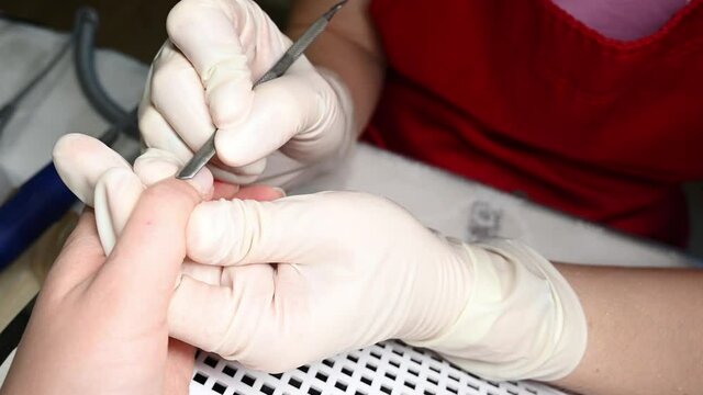Closeup of a nail technician preparing cuticle for cutting. Beauty concept.