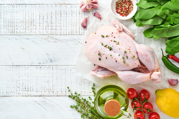 Whole raw chicken with ingredients for making rose pepper, lemon, thyme, garlic, cherry tomato sorrel and salt in the kitchen on light grey slate, stone or concrete background Top view with copy space
