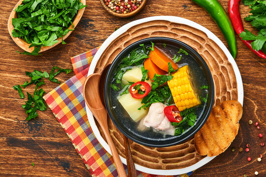 Chilean meat soup with pampkin, corn, fresh coriander and potatoes on old wooden table background. Cazuela. Latinamerican food.