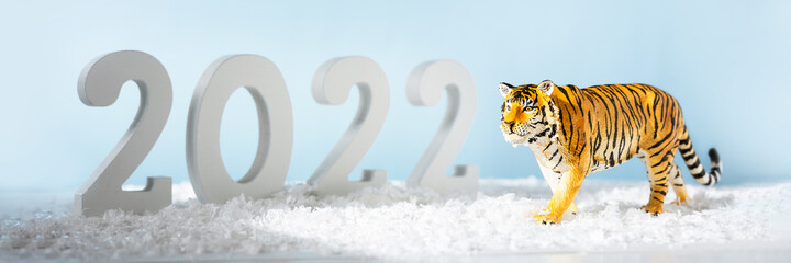 Happy New Year 2022. Decorative white number 2022 and figurine of tiger isolated on blue background. Christmas greeting card. Banner
