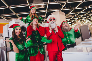 Photo of funky amazed santa claus assistants wear costumes smiling buying domestic appliances...