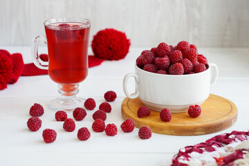 raspberry drink on a gray stone background, walls, glass cup with compote, fresh raspberries on a wooden table, cooling drink