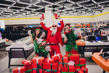 Photo of good mood funky santa claus assistants wear costumes smiling shooting gun holding cash...