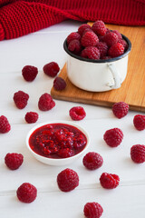 Raspberry jam in glass bowl with spoon isolated on white background