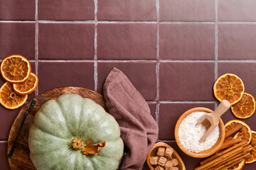 Pumpkin. Autumn food background with cinnamon, nuts and seasonal spices on old ceramic tiles background. Cooking pumpkin or apple pie and cookies for Thanksgiving and autumn holidays. Top view.