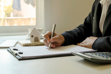 Businessman writing information on a notebook on his desk, working ideas, and taking notes of financial details.