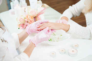 Manicure master holding female hands in a beauty salon.