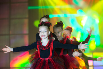 Little girls are performing a dance number. Dance for Helovinna in red suits. Girl dancing. Emotional performance of a children's dance group.